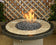 Load image into Gallery viewer, American Fire Products small gray lava stone 1/2 to 1 inch fire pit media use case showing volcanic rock in gas fire pit with flames and decorative fire feature setup