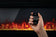 Load image into Gallery viewer, Napoleon Entice electric fireplace remote control held in front of the LED flame display