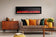 Load image into Gallery viewer, Napoleon Entice 60-inch electric fireplace mounted above a sofa in a modern living room