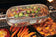 Load image into Gallery viewer, Napoleon rotisserie grill basket made of stainless steel, shown with cooked wings and vegetables on a barbecue grill