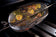 Load image into Gallery viewer, Napoleon rotisserie grill basket made of stainless steel, shown with cooked wings and vegetables on a barbecue grill