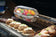 Load image into Gallery viewer, Napoleon rotisserie grill basket made of stainless steel, shown with cooked wings and vegetables on a barbecue grill
