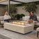 Load image into Gallery viewer, Planika Cabo Fire Table Nacre installed on a modern outdoor patio with decorative flames