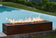 Load image into Gallery viewer, Planika Galio Corten freestanding outdoor gas fireplace installed on a modern patio