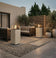 Load image into Gallery viewer, Planika Porto Nacre freestanding fireplace used in a modern outdoor lounge area