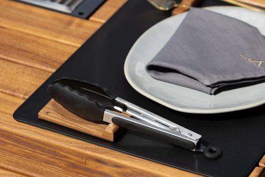 Festavolo Grill Tongs with Wooden Rest placed beside plates on a dining table