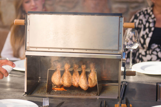 Festavolo Pizza Oven cooking chicken on a grill table