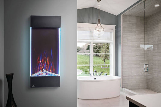 Napoleon Allure Vertical 38-inch electric fireplace with blue accent lighting mounted beside a bathtub