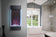 Load image into Gallery viewer, Napoleon Allure Vertical 38-inch electric fireplace with blue accent lighting mounted beside a bathtub
