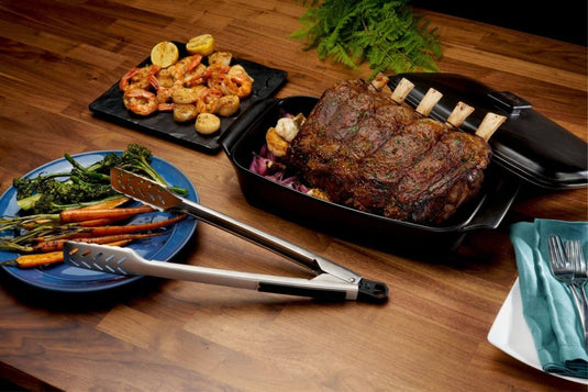 Napoleon GATL008 stainless steel grill tongs displayed beside grilled vegetables and roasted meat