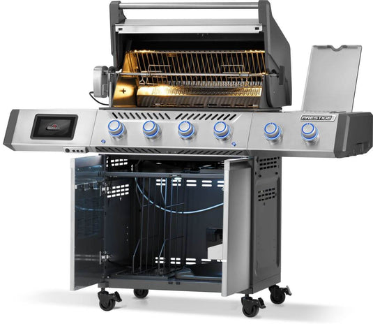 Angled view of Napoleon Prestige PRO 500 with hood and cabinet doors open, showing rotisserie and interior lighting