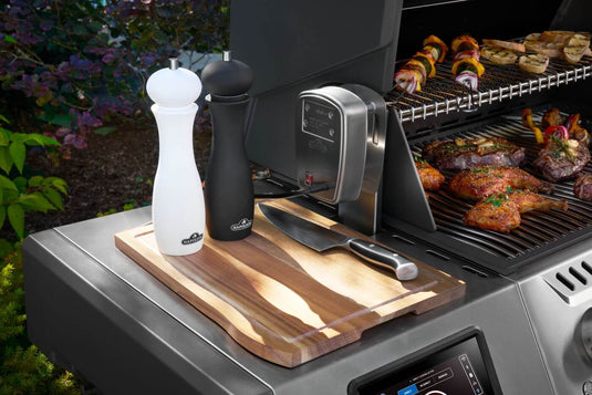 Napoleon Prestige PRO 500 side shelf with cutting board and seasonings beside food on the grill
