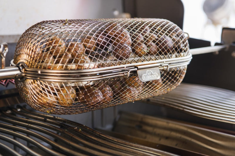 Load image into Gallery viewer, Napoleon rotisserie grill basket made of stainless steel, shown with cooked wings and vegetables on a barbecue grill
