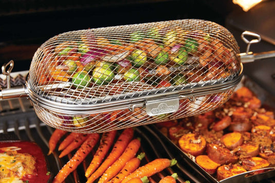 Napoleon rotisserie grill basket made of stainless steel, shown with cooked wings and vegetables on a barbecue grill