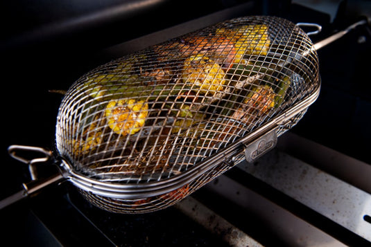 Napoleon rotisserie grill basket made of stainless steel, shown with cooked wings and vegetables on a barbecue grill