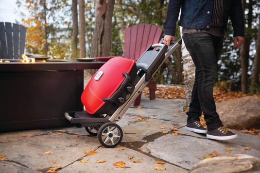 Napoleon TravelQ 285X red portable propane gas grill with scissor cart and reversible cast iron griddle, featuring 2 burners for versatile outdoor cooking