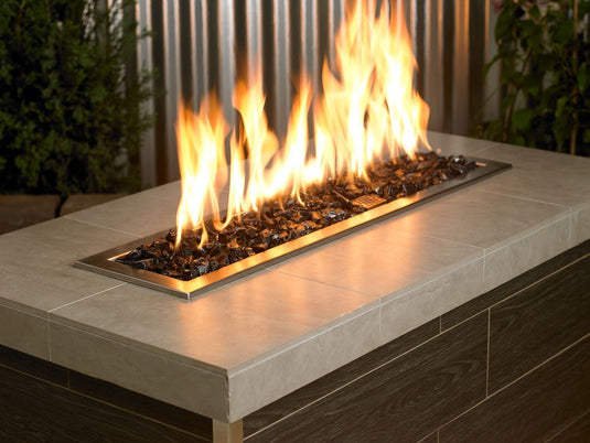 Outdoor fire pit filled with Onyx Medium fire pit glass creating an elegant black glass surface with glowing flames