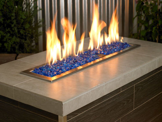 Outdoor fire pit filled with Turquoise Medium fire pit glass creating colorful flames and a modern outdoor living design